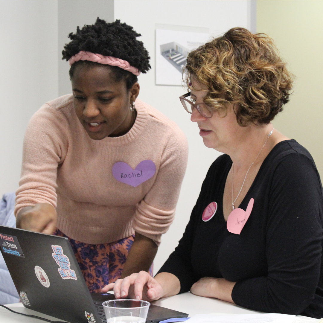 Two women working together in front of a laptop on a transcription