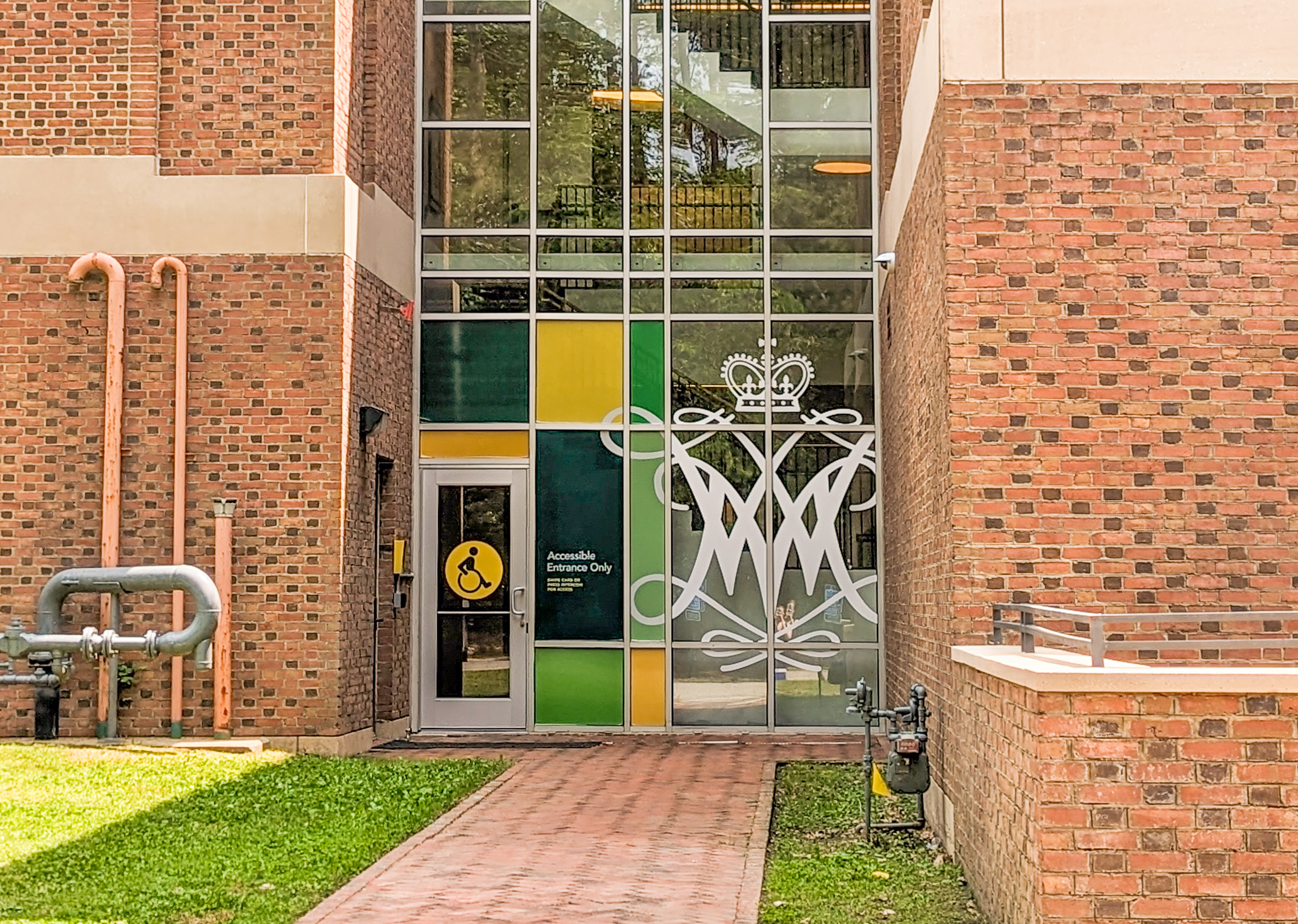 Back entrance to Swem Library marked with a large white cypher and yellow accessibility icon