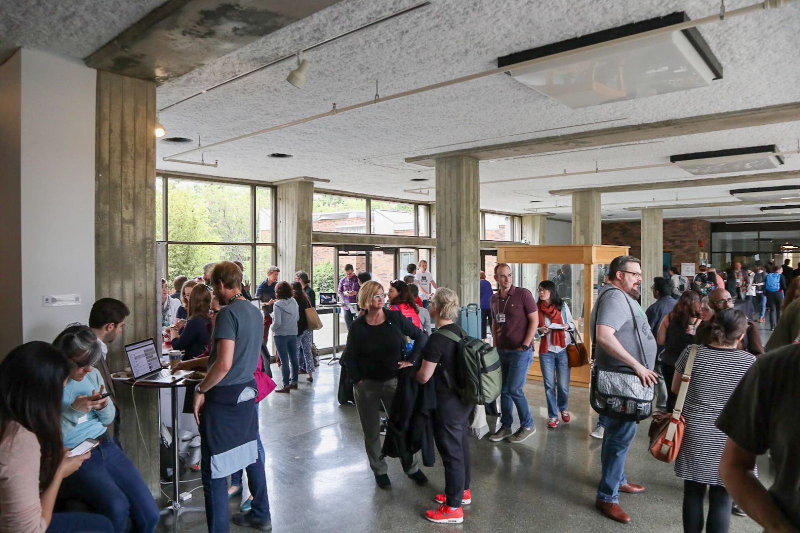 Large group of students talk and share their projects in a bright, glass-walled atrium