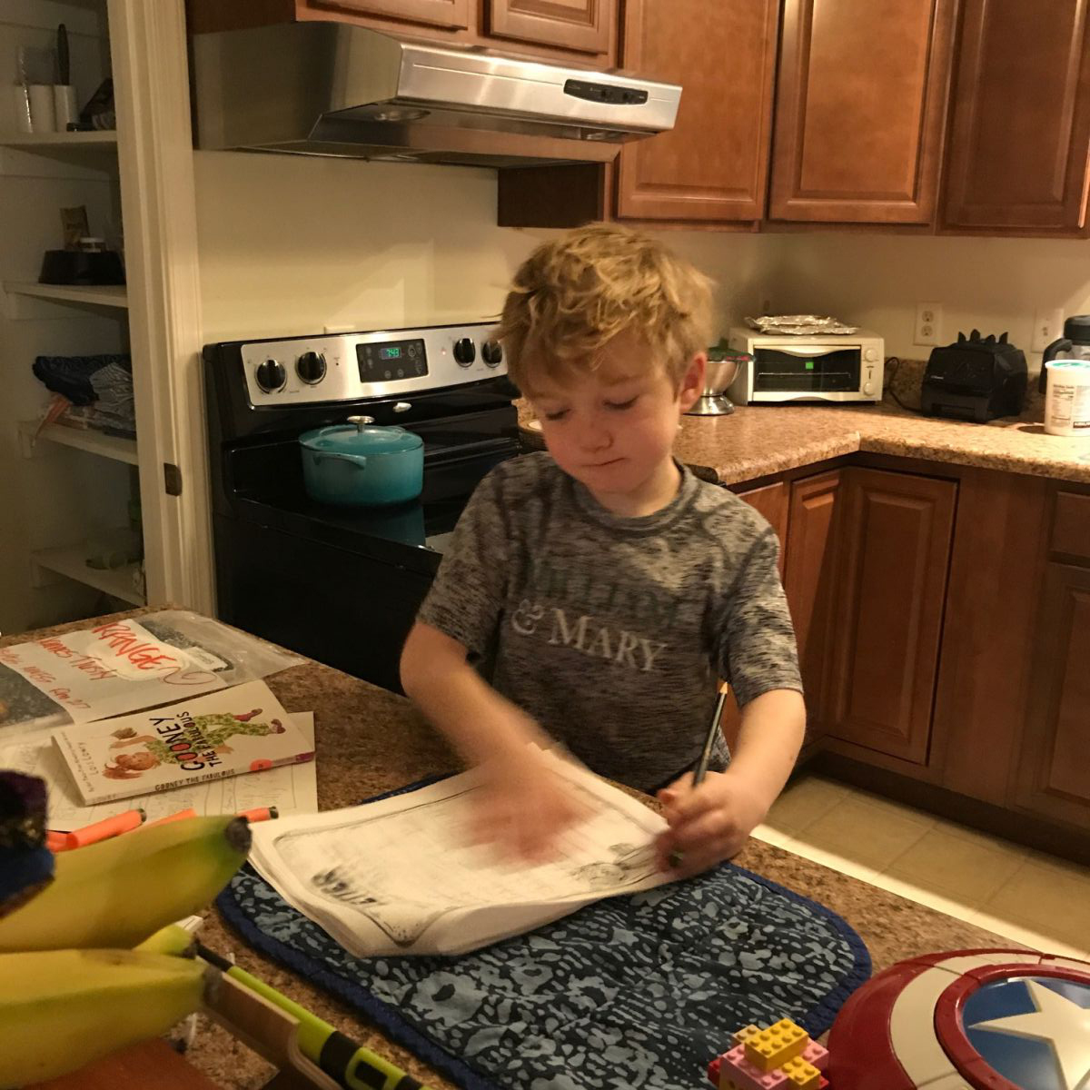 Picture of a 2nd grade boy with blond hair filling out a worksheet in a W&M shirt