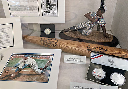 Display case featuring baseball player Jackie Robinson memorabilia incluing a baseball bat and commemorative coins