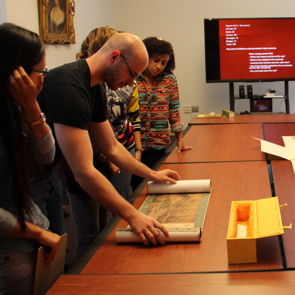 Student opens facsimile handscroll in Special Collections class session