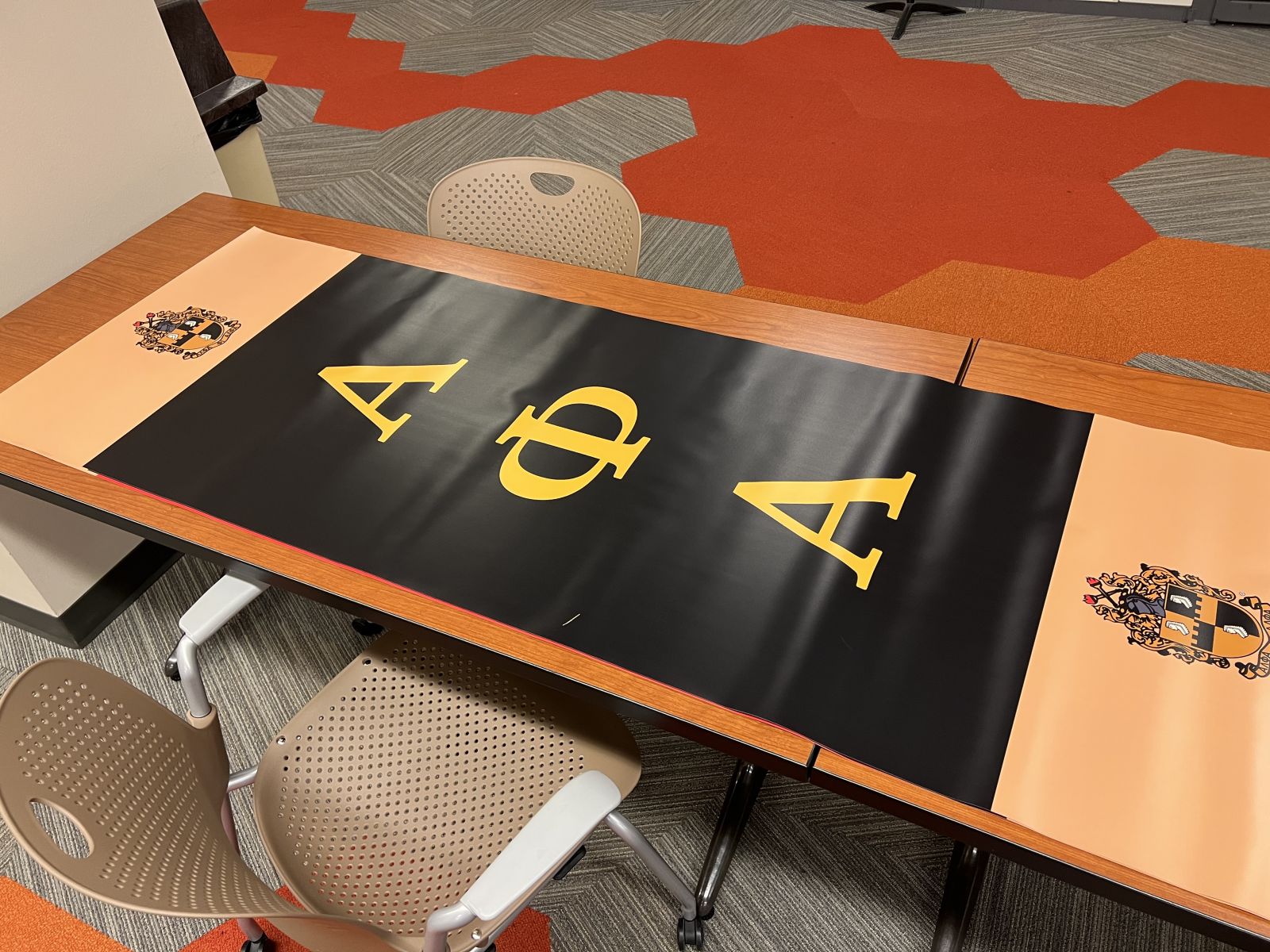 A banner for Alpha Phi Alpha is unrolled on a table outside of the print shop on the Ground Floor of Swem Library.
