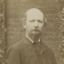 Cabinet card portrait of Algernon Charles Swinburne standing in front of steps and ivy covered brickwork