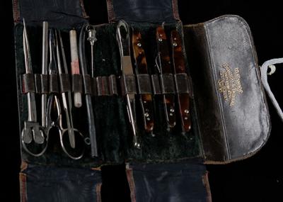 Open black leather surgical kit with various steel tools.