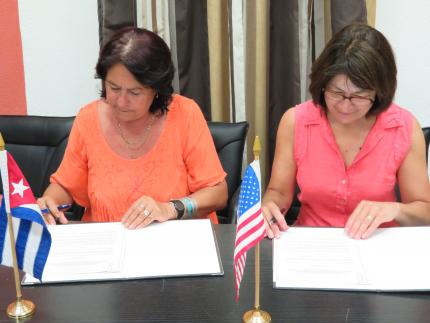 Caridad Rojas Zayas and Ann Marie Stock signing agreement
