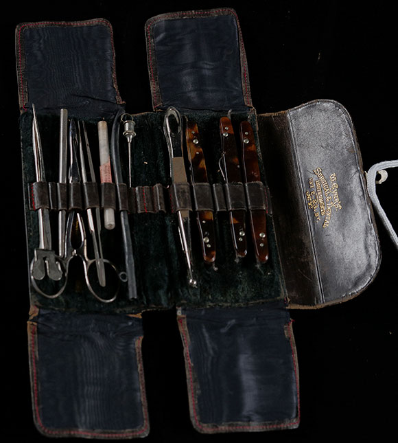 Open black leather surgical kit with various steel tools.